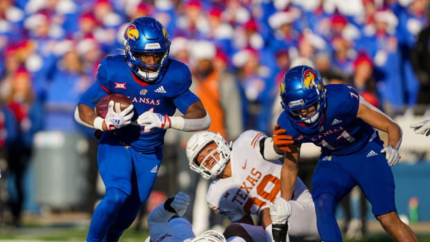 Nov 19, 2022; Lawrence, Kansas, USA; Kansas Jayhawks running back Devin Neal (4) runs the ball against Texas Longhorns defensive end Ovie Oghoufo (18) and defensive back Jerrin Thompson (28) during the first half at David Booth Kansas Memorial Stadium. Mandatory Credit: Jay Biggerstaff-USA TODAY Sports